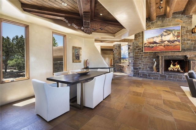 dining room featuring beam ceiling, a fireplace, and wooden ceiling