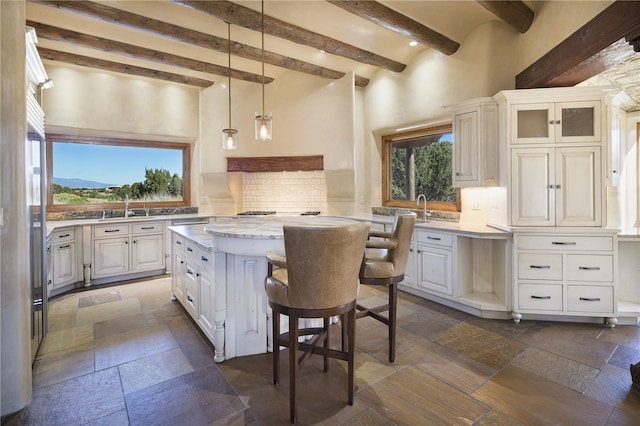 kitchen with a breakfast bar, white cabinets, backsplash, a center island, and light stone countertops