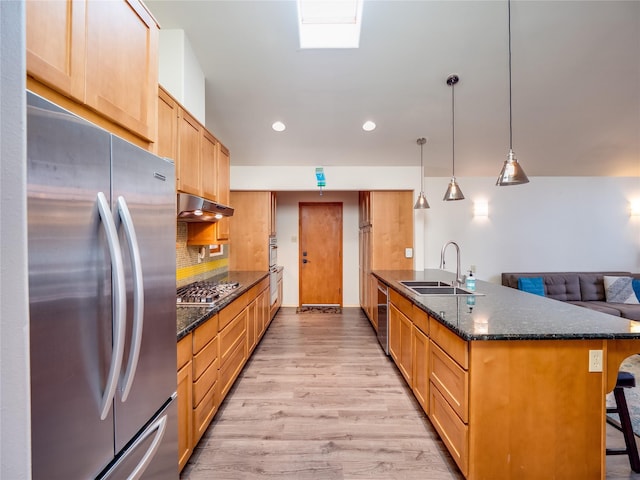 kitchen with sink, hanging light fixtures, dark stone countertops, appliances with stainless steel finishes, and a kitchen breakfast bar