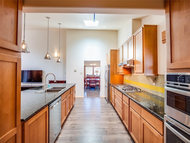 kitchen featuring decorative light fixtures, tasteful backsplash, sink, dark stone countertops, and stainless steel appliances