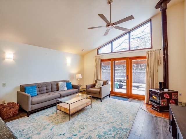 living room featuring ceiling fan, high vaulted ceiling, hardwood / wood-style floors, and a wood stove