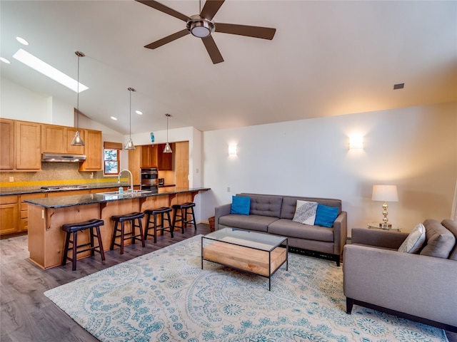 living room with sink, dark wood-type flooring, vaulted ceiling with skylight, and ceiling fan