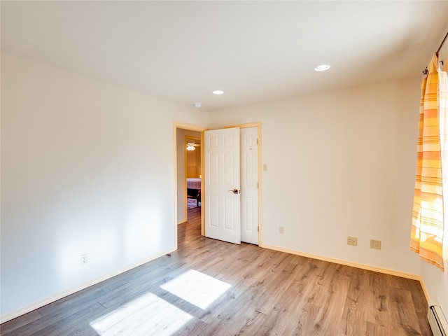 spare room featuring baseboard heating and light wood-type flooring