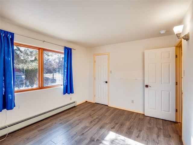 unfurnished room featuring a baseboard radiator and hardwood / wood-style floors