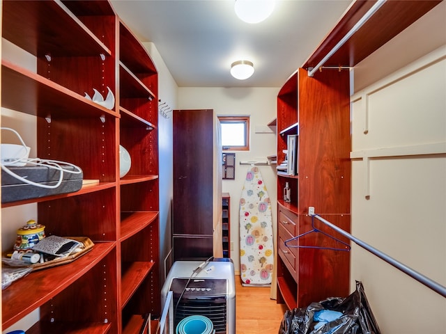 walk in closet with light hardwood / wood-style flooring