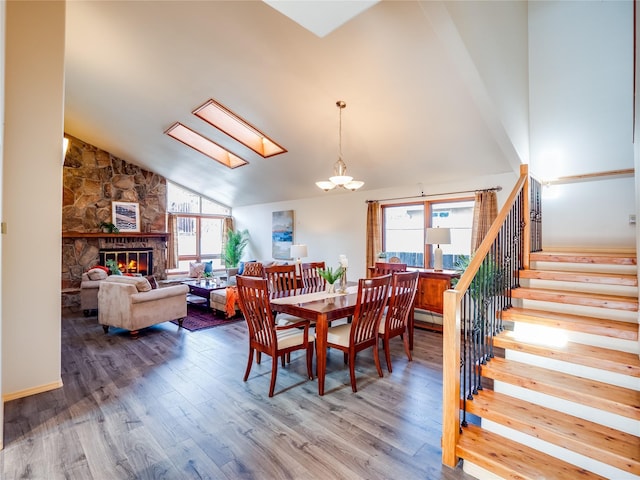 dining area featuring a skylight, a stone fireplace, a wealth of natural light, and hardwood / wood-style flooring