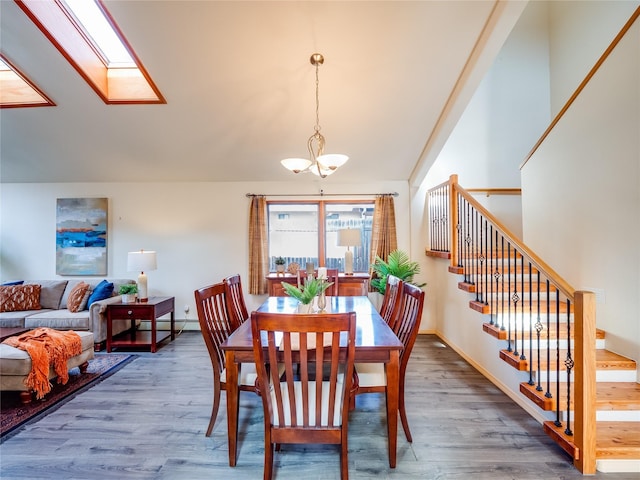 dining area with a baseboard radiator, a chandelier, hardwood / wood-style floors, and a skylight