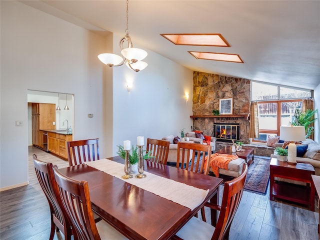 dining room with lofted ceiling with skylight, sink, hardwood / wood-style floors, and a fireplace