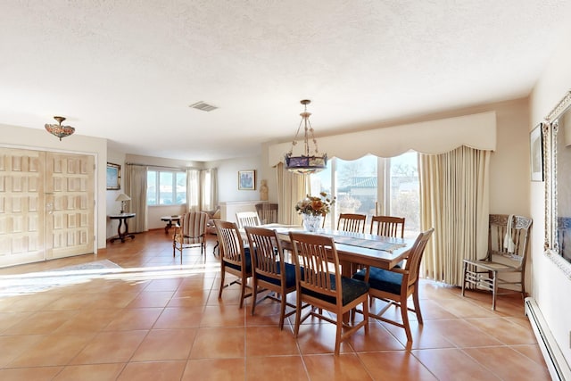 dining room featuring a baseboard radiator, light tile patterned floors, and a textured ceiling