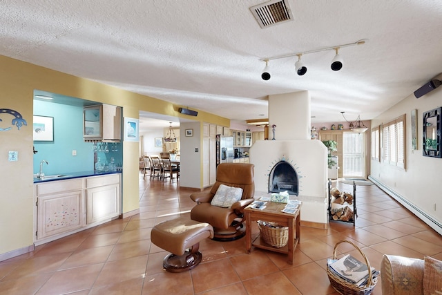 tiled living room with sink, track lighting, and a textured ceiling