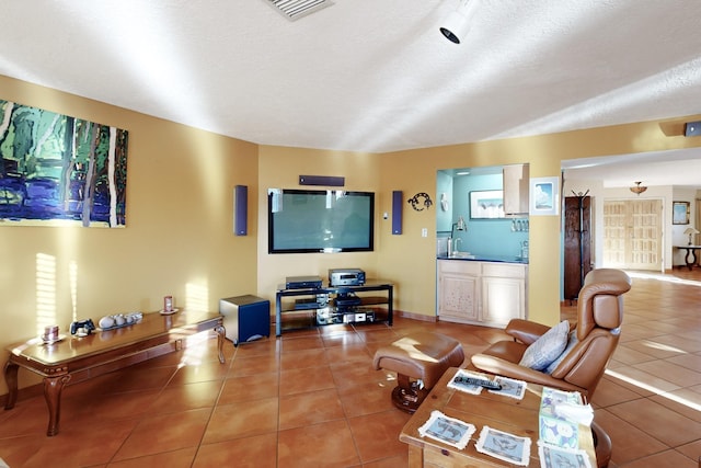 tiled living room featuring sink and a textured ceiling