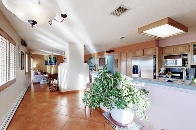 interior space with light brown cabinetry, stainless steel fridge with ice dispenser, a textured ceiling, light tile patterned floors, and a baseboard radiator