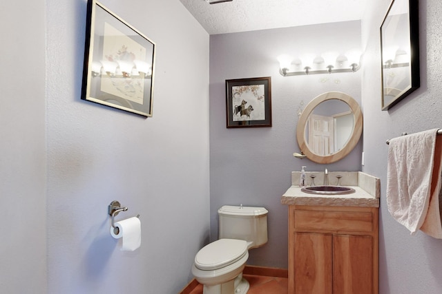 bathroom with vanity, toilet, tile patterned flooring, and a textured ceiling