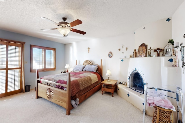 bedroom featuring a textured ceiling, light colored carpet, and ceiling fan