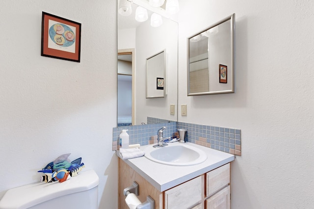 bathroom with vanity, backsplash, and toilet