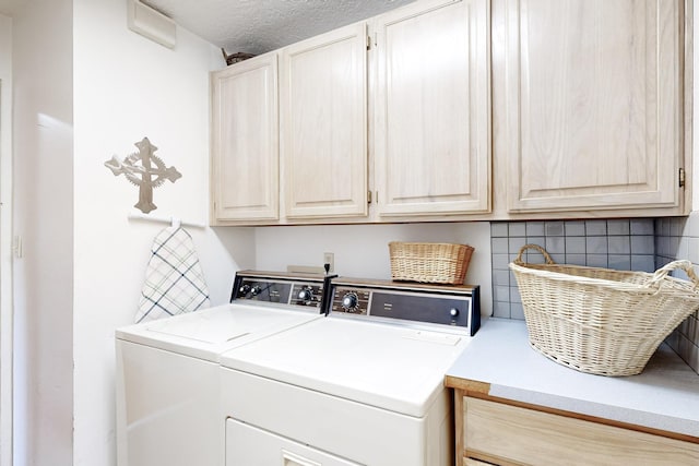 washroom with independent washer and dryer, cabinets, and a textured ceiling