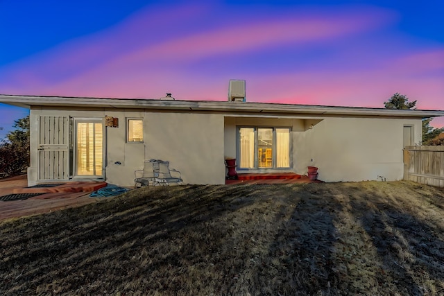 back house at dusk featuring a lawn