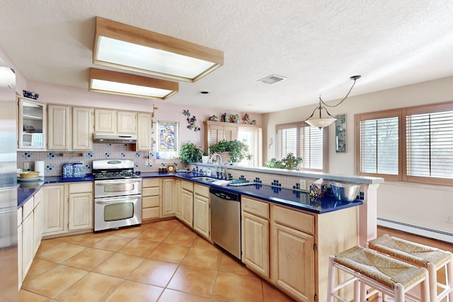 kitchen with a kitchen bar, sink, decorative light fixtures, a wealth of natural light, and stainless steel appliances