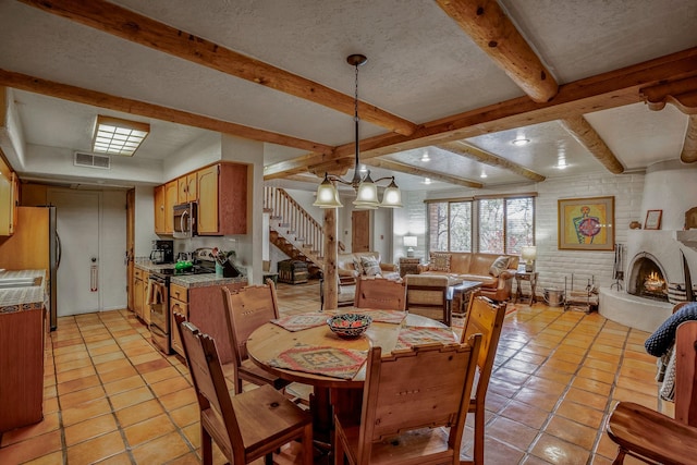 tiled dining room with beam ceiling, a fireplace, a textured ceiling, and brick wall