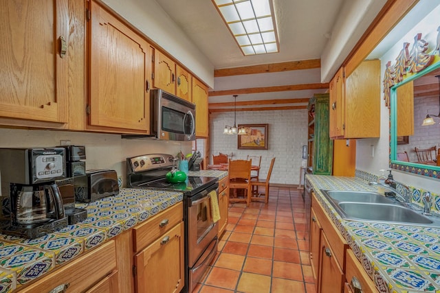 kitchen with brick wall, sink, hanging light fixtures, light tile patterned floors, and stainless steel appliances