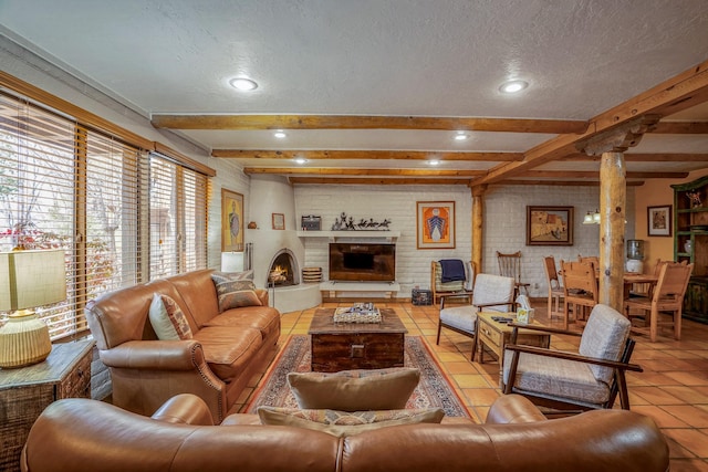 living room with light tile patterned flooring, brick wall, beamed ceiling, decorative columns, and a large fireplace