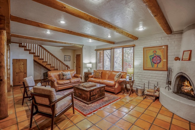 tiled living room featuring beamed ceiling, a large fireplace, and a textured ceiling