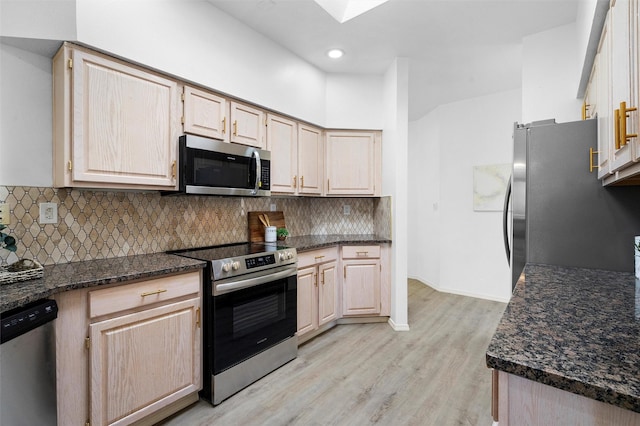 kitchen with light hardwood / wood-style flooring, stainless steel appliances, tasteful backsplash, light brown cabinetry, and dark stone counters