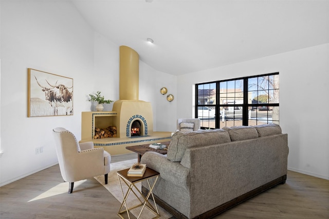 living room featuring vaulted ceiling, light wood-type flooring, and a fireplace