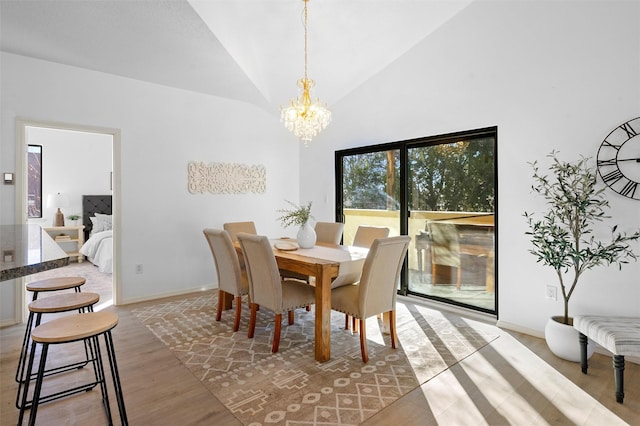 dining area with high vaulted ceiling, hardwood / wood-style floors, and an inviting chandelier