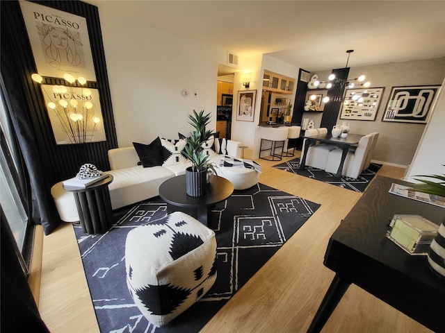 living room featuring visible vents, a notable chandelier, and wood finished floors