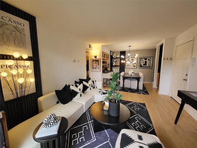 living room with visible vents, a chandelier, and wood finished floors