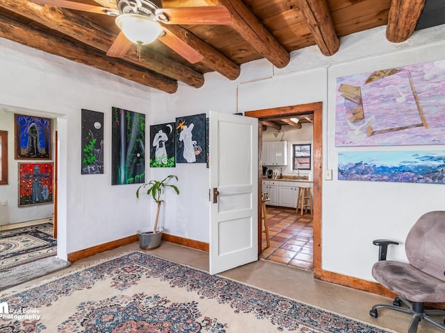 interior space featuring a ceiling fan, wooden ceiling, baseboards, and beamed ceiling
