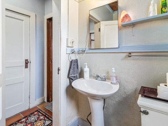 bathroom featuring a textured wall and tile patterned flooring
