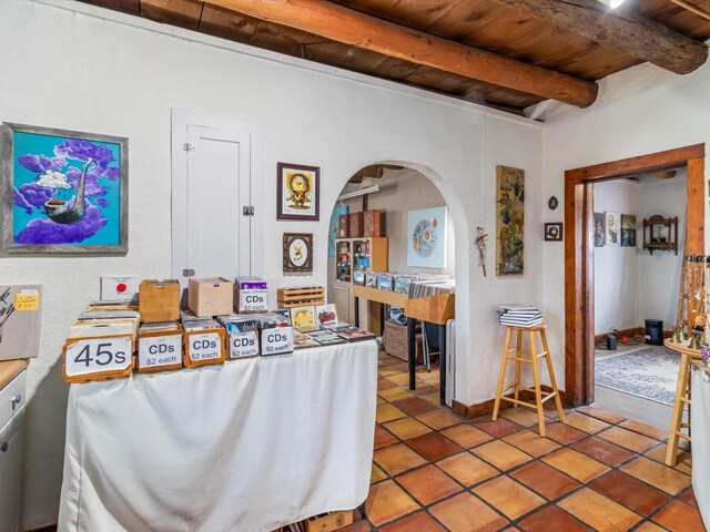 dining room with arched walkways, tile patterned floors, wood ceiling, and beam ceiling