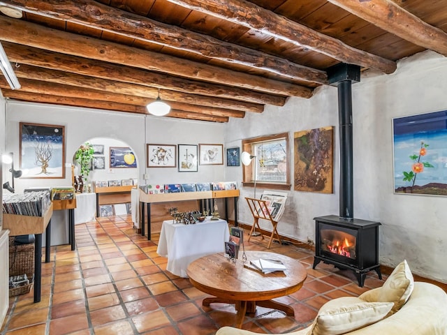 living room with beamed ceiling, tile patterned flooring, a wood stove, and wooden ceiling