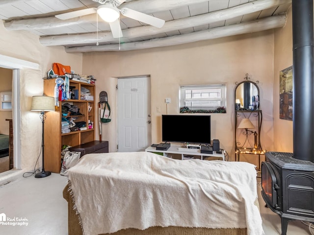 bedroom with beamed ceiling, ceiling fan, wooden ceiling, and a wood stove