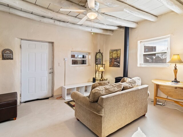 living area with finished concrete flooring, beam ceiling, wood ceiling, and a ceiling fan