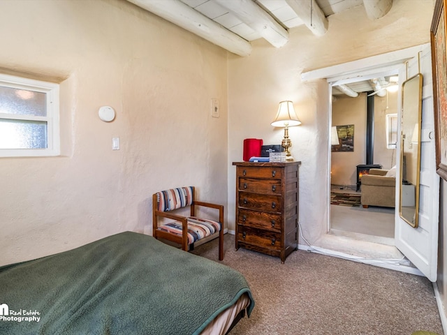 carpeted bedroom featuring a wood stove, wooden ceiling, and beam ceiling