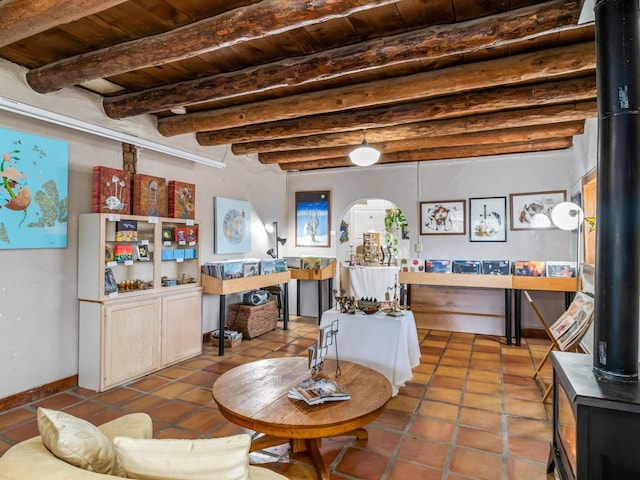 interior space with a wood stove, wooden ceiling, and beam ceiling