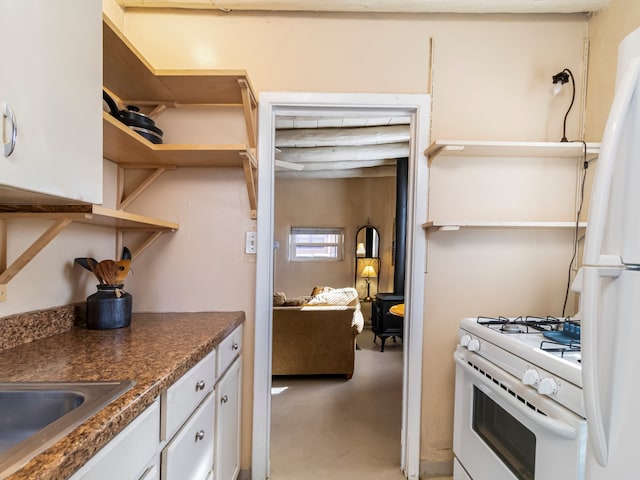 kitchen featuring open shelves, concrete floors, white appliances, dark countertops, and white cabinets