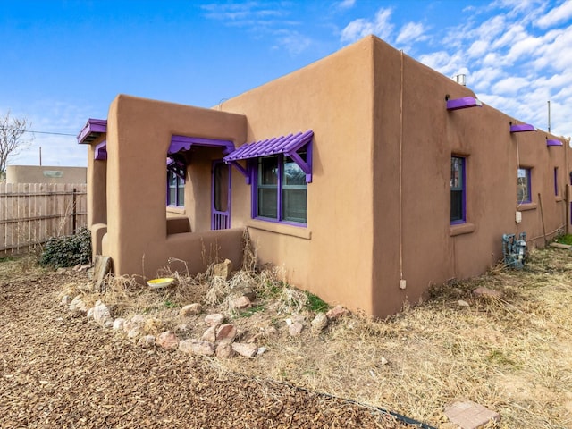 view of side of home featuring stucco siding and fence