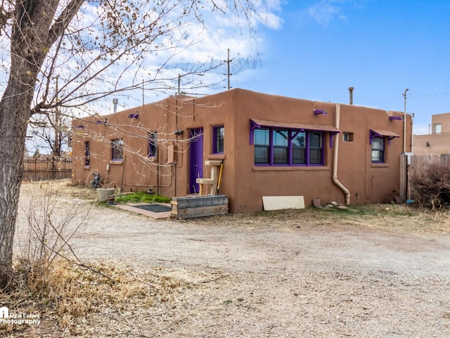 view of front facade with stucco siding and fence