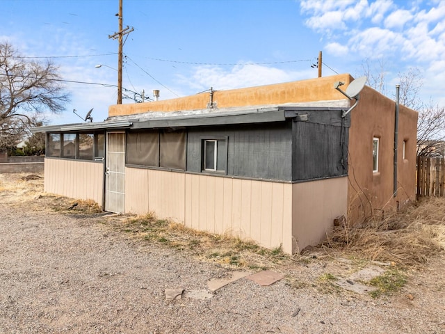 view of side of home with a sunroom and fence