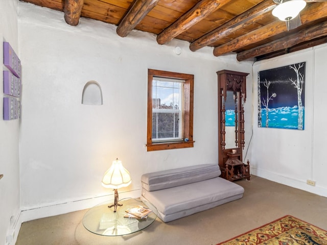 living area featuring baseboards, wooden ceiling, and beam ceiling