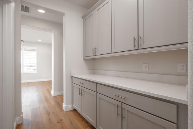 bar with gray cabinets and light hardwood / wood-style floors