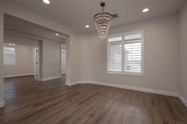 spare room featuring dark hardwood / wood-style floors and a notable chandelier