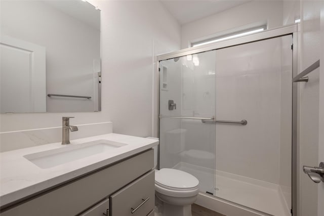 bathroom featuring vanity, toilet, and a shower with door