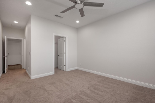 unfurnished bedroom with light carpet, a spacious closet, and ceiling fan