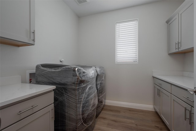 clothes washing area with cabinets, hookup for a washing machine, and light hardwood / wood-style flooring