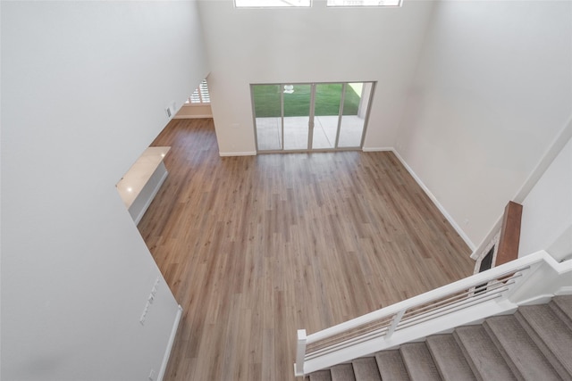 unfurnished living room featuring a towering ceiling and light hardwood / wood-style flooring